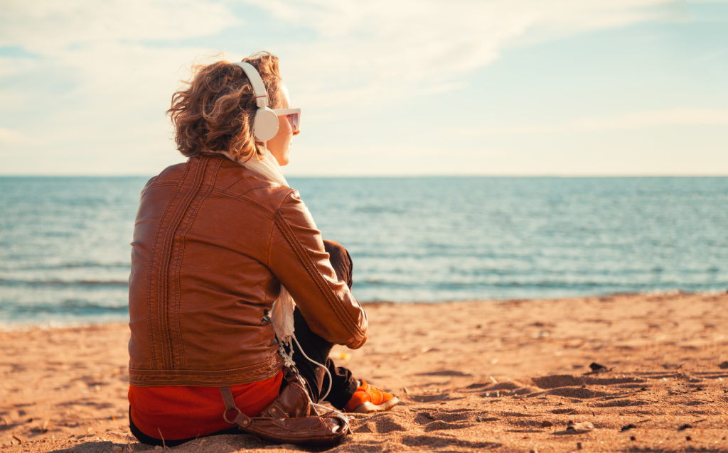 Young woman in a headphones at the beach