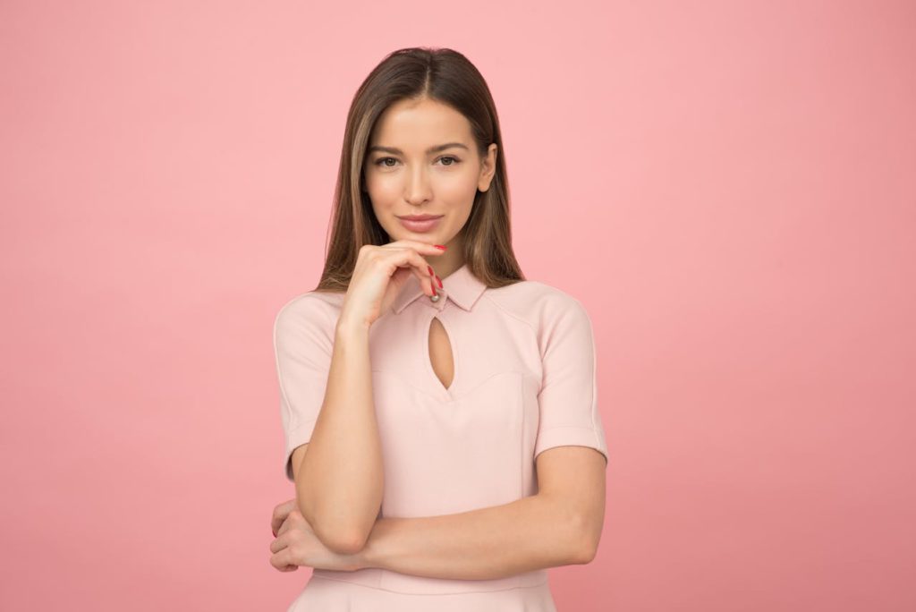 A girl smiling amid a pink background